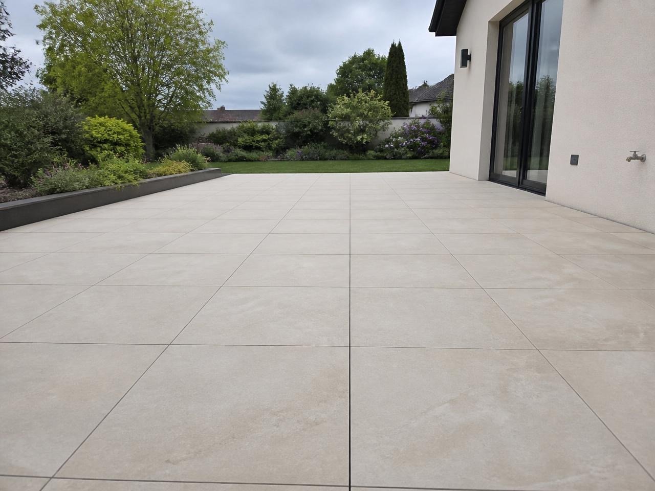 Fertige Terrasse mit Feinsteinzeugplatten in heller Natursteinoptik am Einfamilienhaus